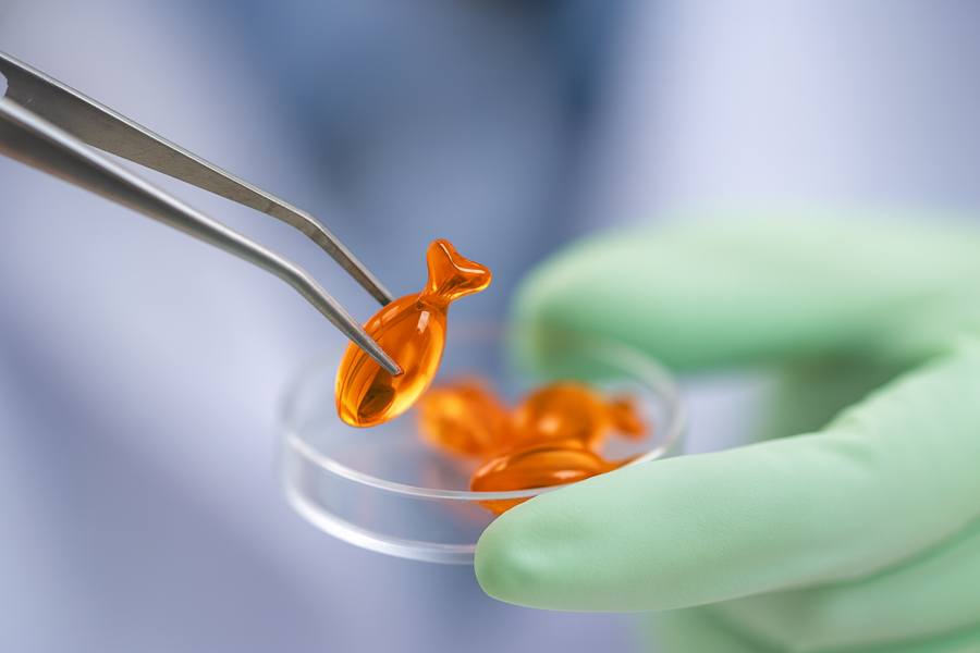 Laboratory technician inspecting fish oil capsules during quality control and third-party testing.